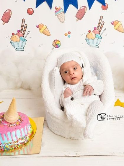 A wider view of the sweet treats-themed newborn session, showing the full setup with pink balloons, gift boxes, and a festive banner.