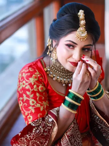 A close-up of the bride adjusting her `nath`, a classic and intimate bridal moment.