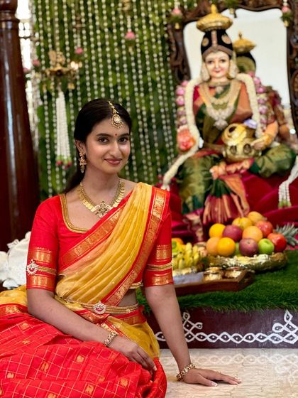 Our client celebrating a traditional ceremony. Her custom red blouse for the half saree ensemble was designed to be both comfortable and elegant for the occasion.