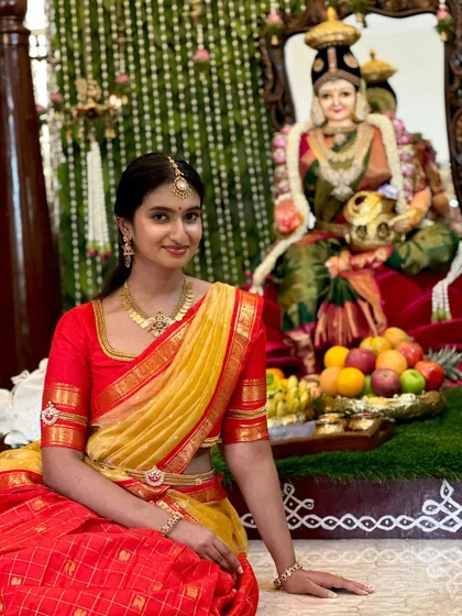 Our client seated during a traditional ceremony, looking graceful in her custom half-saree. The rich colors and classic design make it ideal for religious functions and festivals.