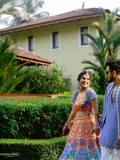 A sweet moment between the couple during their vibrant Goa Mehendi, walking through the lush gardens of the resort.