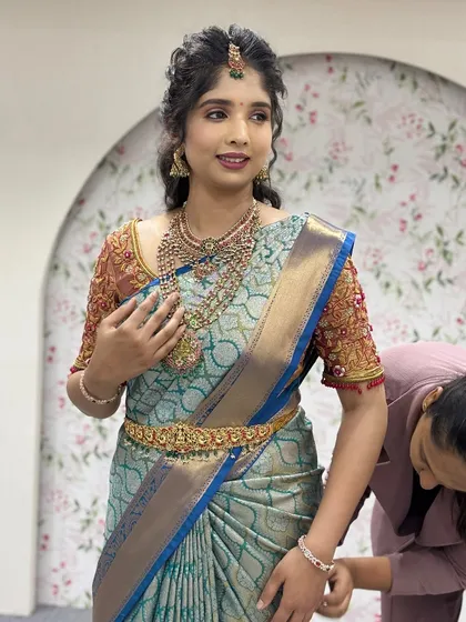 A close-up of the final adjustments. The focus is on ensuring the pallu sits perfectly on the shoulder and the pleats are secure for a long-lasting, elegant look.