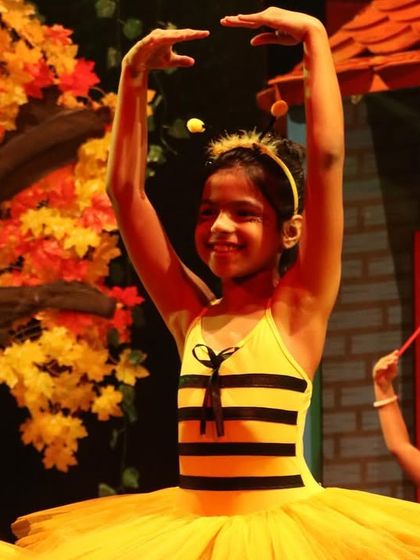 A smiling bumblebee on stage. We encourage our young dancers to express joy and have fun during their performances.