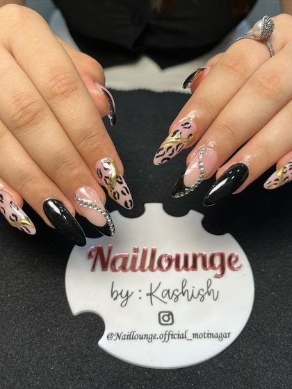 A wild and glamorous set combining black nails, leopard print, and sparkling rhinestone swirls.