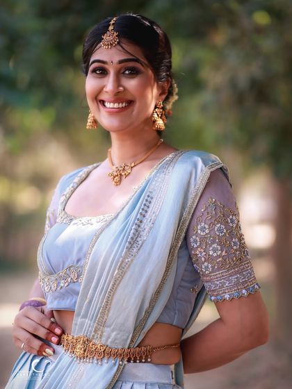 A stunning close-up that captures her radiant smile and the intricate details of her traditional jewelry and attire. The soft natural light is incredibly flattering.