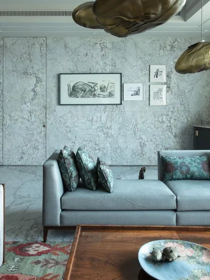 A serene corner of the living room in our Kolkata project, featuring a custom sofa and framed art against a textured stone wall. The design emphasizes tranquility and understated luxury.