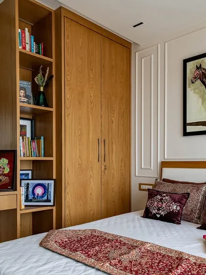 The guest bedroom in the 'Eternity' project. The room features warm wood furniture, a vanity with a large mirror, and classic artwork, creating a comfortable and elegant space for guests.