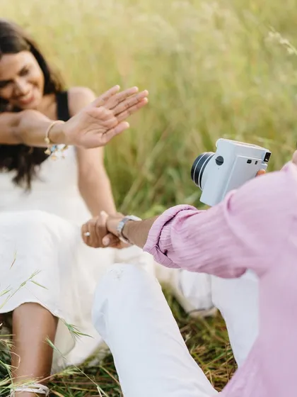 A fun, candid moment during their polaroid session. Her playful gesture to the camera shows her personality and the comfortable, easygoing nature of their relationship.