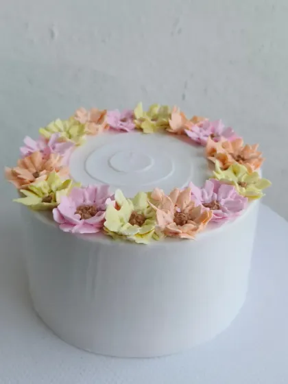 A clean white cake with a beautiful wreath of pastel-colored buttercream flowers.