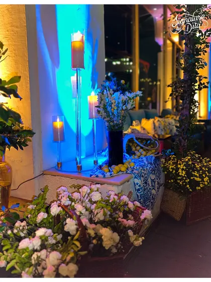 This corner is overflowing with baskets of white and yellow flowers, with tall candles providing vertical light, creating a lush and abundant feel.