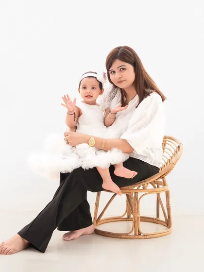 A mother and daughter share a moment. The clean white background and simple rattan chair create a timeless setting for this sweet portrait.
