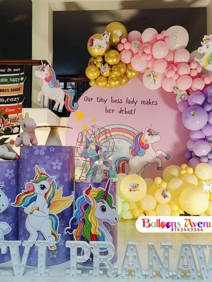 A magical unicorn-themed birthday party with a custom backdrop, unicorn cutouts, and a pastel and gold balloon garland.