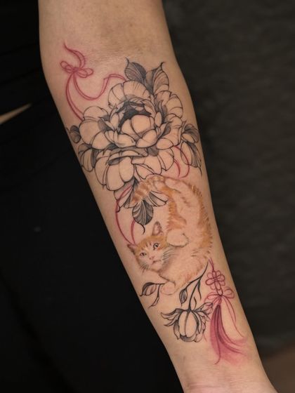 A beautiful illustrative tattoo combining a realistic ginger cat portrait with fine-line peonies and decorative ribbons. A touching tribute to a furry family member.