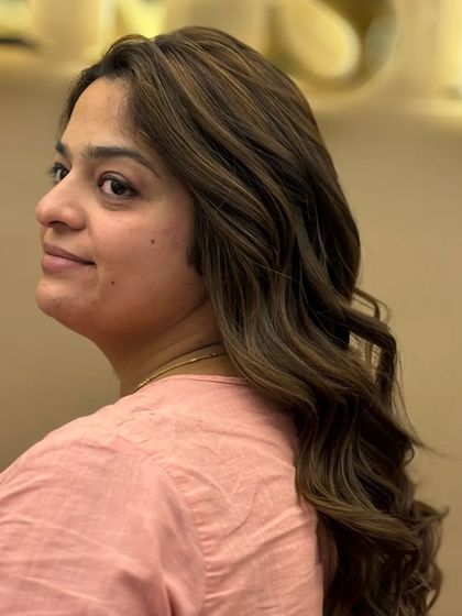 A happy client showing off her new hair color. The blend of highlights adds a vibrant, healthy shine that transforms her entire look.