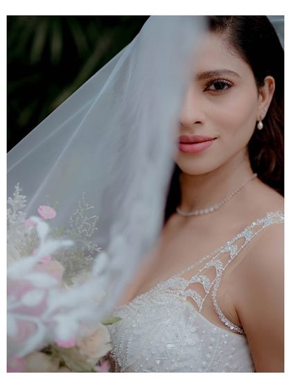An artistic portrait of the bride, her face partially obscured by her veil, creating a sense of mystery and anticipation.