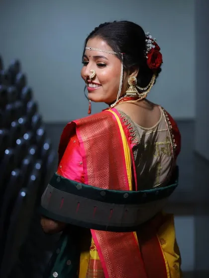 A back view of the bride, showing off her elegant hairstyle with a red rose and traditional Maharashtrian hair accessories.