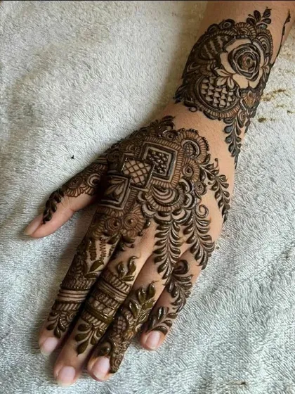 A stunning bridal design featuring a large, bold floral motif on the wrist and intricate geometric patterns on the hand.