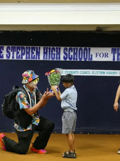 A young boy presents flowers to the 'Silent Storyteller', with a volunteer looking on proudly. These moments of connection between guest artists, children, and our team are truly special.