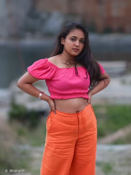 A confident pose against a blurred natural backdrop. The colors of the outfit pop, making for a vibrant lifestyle portrait.