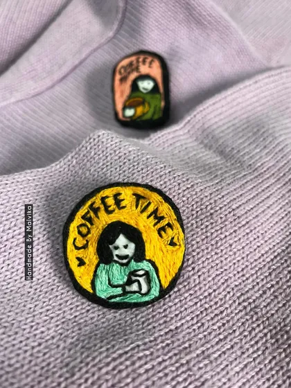 A different angle on my 'Coffee Time' badges, showing the texture of the embroidery against a soft sweater. These handmade pins are a cozy and fun accessory for anyone fueled by caffeine and creativity.