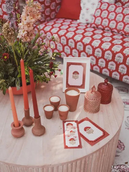 A tabletop at the "Red Affair," styled with terracotta candle holders, custom stationery, and floral-printed lampshades.