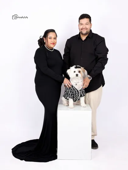 A complete family portrait in our studio, with the couple and their well-dressed dog posing together.