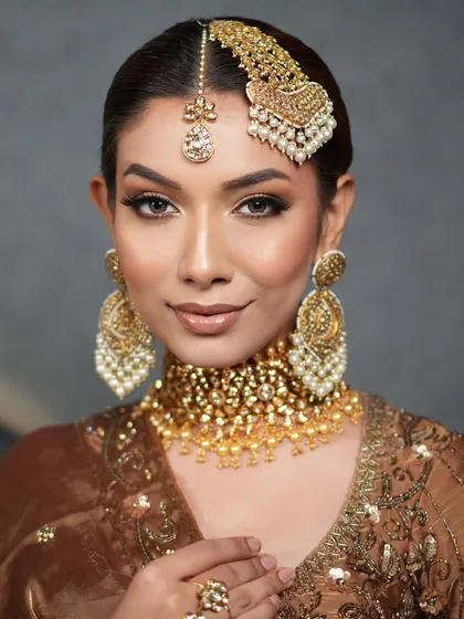 A regal bridal look with a sleek, low ponytail that transitions into a thick, traditional braid, perfect for supporting a heavy passa or jhoomar.