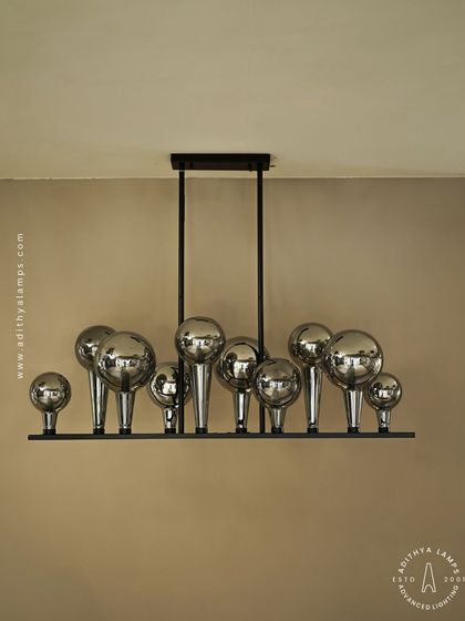 A playful yet chic linear chandelier featuring a series of chrome-finished glass bubbles. The highly reflective surface and modern design make it a striking addition to a kitchen island or a contemporary dining space.