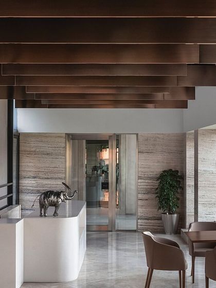 The director's lounge on the top floor of 'The Layered Office' features a unique ceiling treatment with layered copper-toned panels. This space connects to a large boardroom and an outdoor terrace with expansive views.