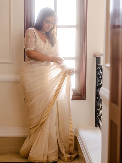 A soft, ethereal moment with Kajol in a white chiffon saree by a window, inspired by the timeless elegance of Indian cinema.