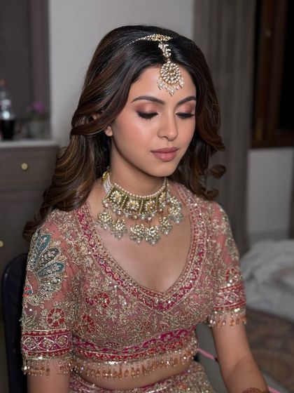 A quiet moment of reflection. The soft lighting highlights the shimmer on her eyelids and the subtle contouring of her cheeks.