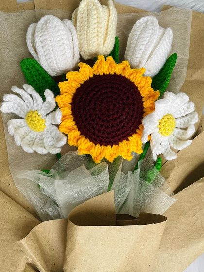 A close-up of the rustic bouquet with a sunflower, tulips, and daisies. The brown paper wrapping gives it a wonderfully warm and natural feel.