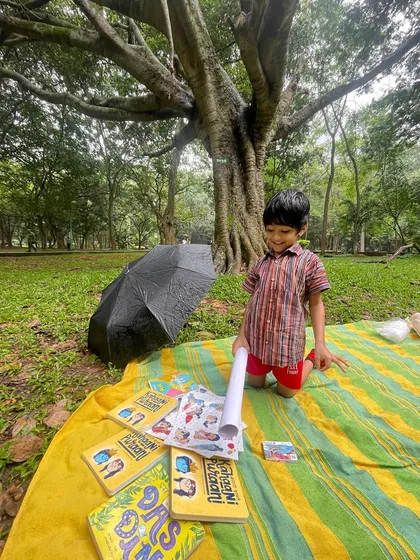 A young boy proudly kneels over his collection of books and sticker sheets. Providing materials for creative expression is a key part of our workshop philosophy.