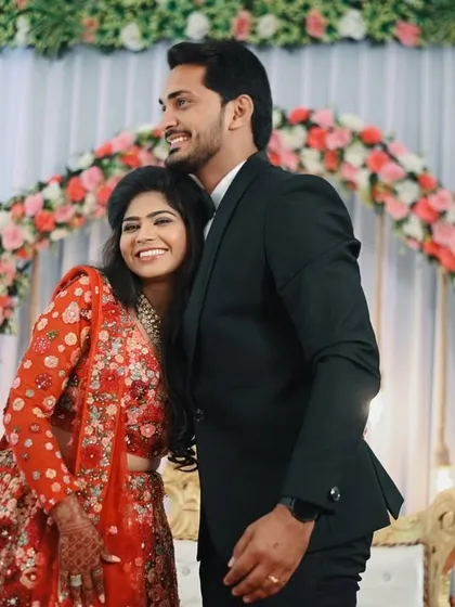 A warm, happy hug after the proposal. This photo radiates the comfort and joy the couple feels, captured against the beautiful floral decor of their engagement stage.
