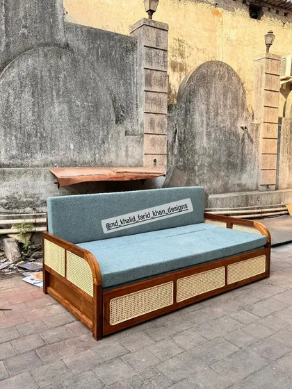 This is a custom-designed sofa bed, perfect for multi-functional spaces. It features a solid teak wood frame with cane paneling and a comfortable, easy-to-convert mattress, offering both a stylish sofa and a practical guest bed.