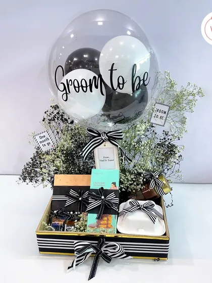 Spoil the groom-to-be with this exclusive hamper. It features a "Groom to be" balloon, gourmet snacks, and mini liquor bottles, all in a sophisticated black and white theme.