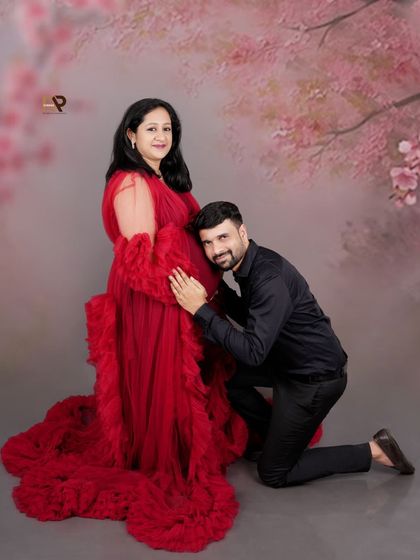 A beautiful maternity portrait against a soft, cherry blossom-themed backdrop. The red gown provides a stunning pop of color, making this a truly eye-catching photo.