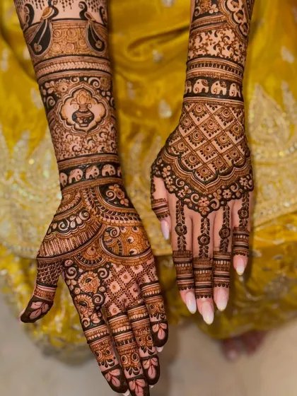 This symmetrical bridal design is filled with traditional elements like elephants and kalash symbols. The grid pattern on the back of the hands adds a modern touch to the classic motifs.