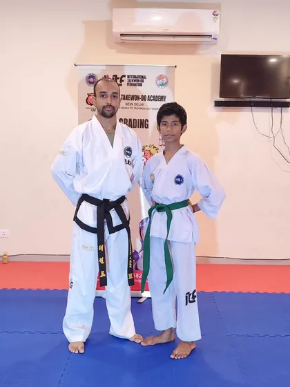 Posing with a student after his successful belt promotion. Each new belt, like this green belt, marks a significant step in a martial artist's journey.