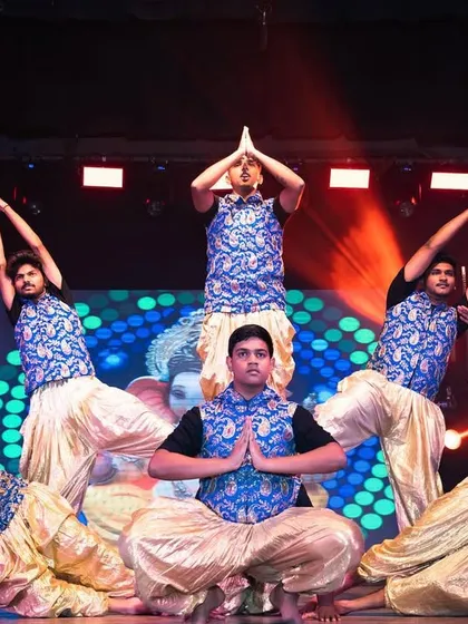 Dancers in a synchronized pose during their performance. The red overhead lighting and the textured background on the screen create a powerful and dramatic visual effect.