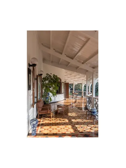 Sunlight streams across the restored veranda, illuminating the beautiful tile floor and the exposed beam ceiling. This is a space designed for quiet contemplation, connecting the interior with the surrounding nature.