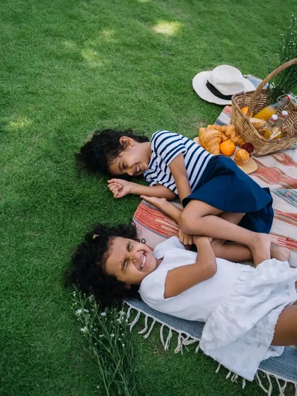 The pure joy of sisterhood captured during an outdoor picnic. I create a fun and relaxed atmosphere to encourage these genuine moments of laughter and play.
