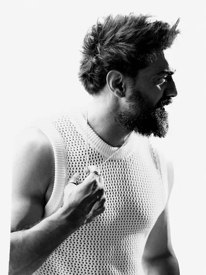A profile shot of Dev in black and white. This angle emphasizes his strong jawline and rugged beard, creating a classic and masculine portrait.