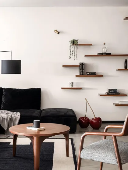 A quirky detail in the Ebony & Ivory living room, where a giant cherry sculpture adds a pop of color and personality. The space features a custom black sofa, a walnut coffee table, and a modern armchair.