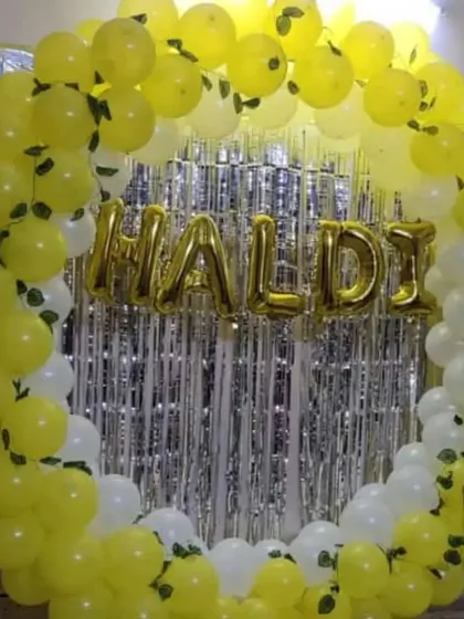 A bright and sunny Haldi decoration. The ring of yellow and white balloons with green leaf accents and a "Haldi" foil banner creates the perfect festive vibe.