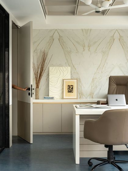 The CEO cabin features a stunning book-matched marble wall that serves as an artistic backdrop to the workspace. The design balances this opulent feature with minimalist furniture and a calm color scheme.