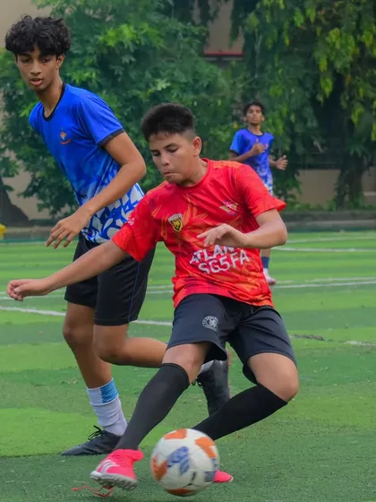 A U15 player in our red kit driving forward with the ball during the MBPL game.