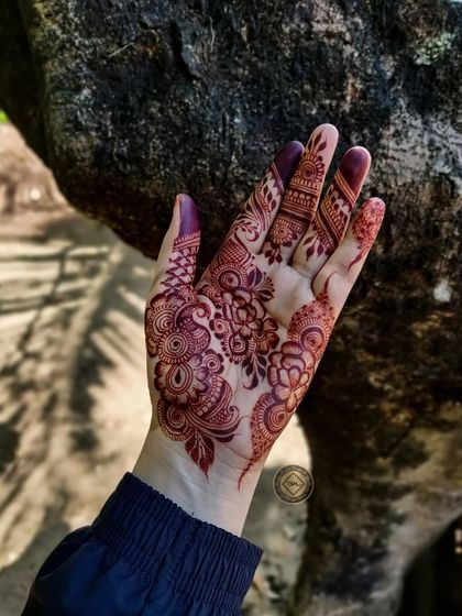 A close-up of a mature henna stain in a natural, outdoor setting. The deep color looks beautiful against the backdrop of the tree bark.