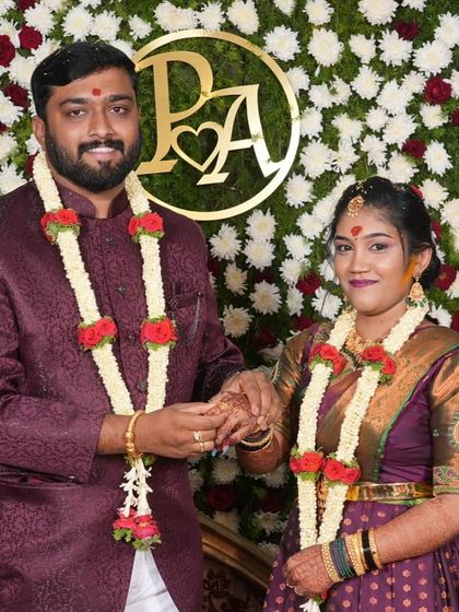 A happy couple during their engagement ceremony. The bride's makeup is traditional, with a touch of turmeric, complementing her purple silk saree and gold jewelry.
