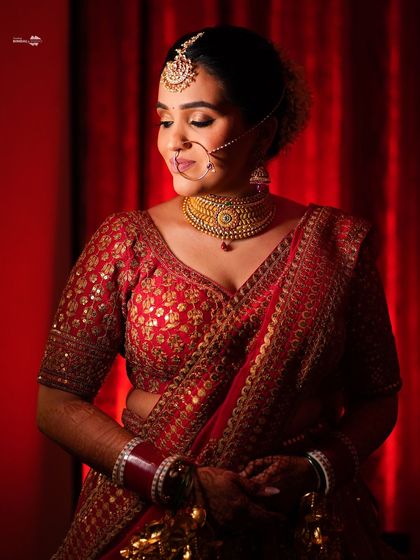 An elegant portrait of the bride against a rich, red background. Her traditional jewelry and serene expression are beautifully captured.